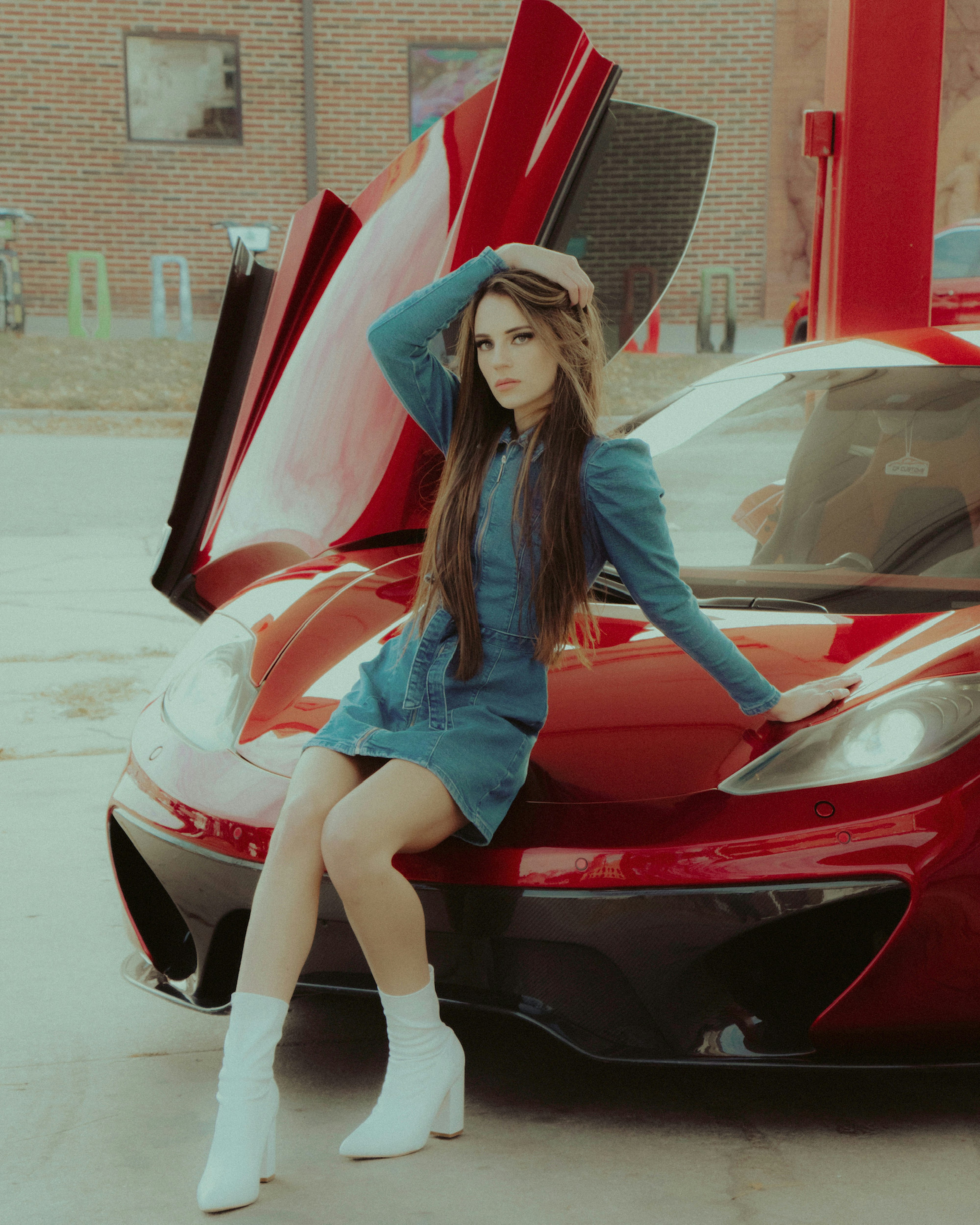 woman in blue long sleeve shirt and white denim shorts sitting on red car